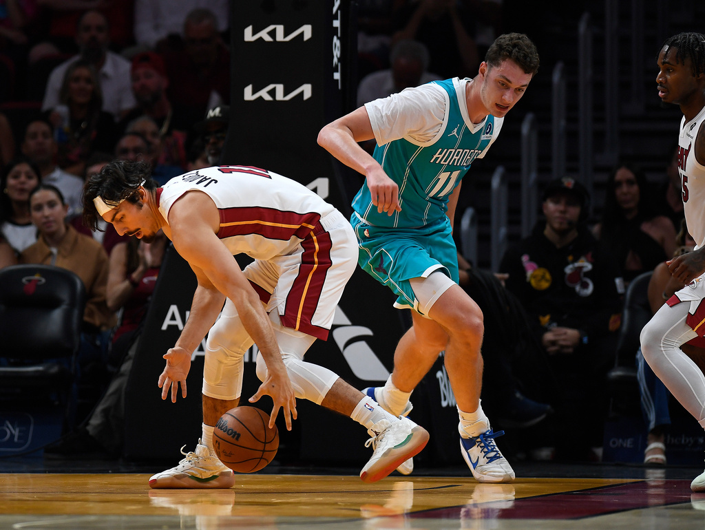 Miami Heat guard Jaime Jaquez Jr. (11) picks up the ball in front of Charlotte Hornets center Ryan Kalkbrenner (11) during the first half of an NBA basketball game, Tuesday, Oct. 28, 2025, in Miami. (AP Photo/Michael Laughlin)