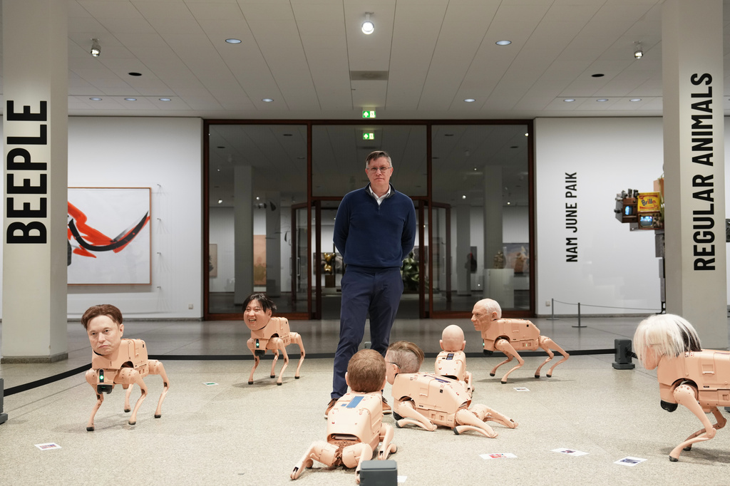 Artist Beeple, Mike Winkelmann, poses inside his installation titled Regular Animals, with robots in the likeness of Elon Musk, left, Kim Jong Un, second left, Pablo Picasso, second right, and Andy Warhol, right, at the Neue Nationalgalerie museum in Berlin, Germany, Tuesday, April 28, 2026. (AP Photo/Markus Schreiber)