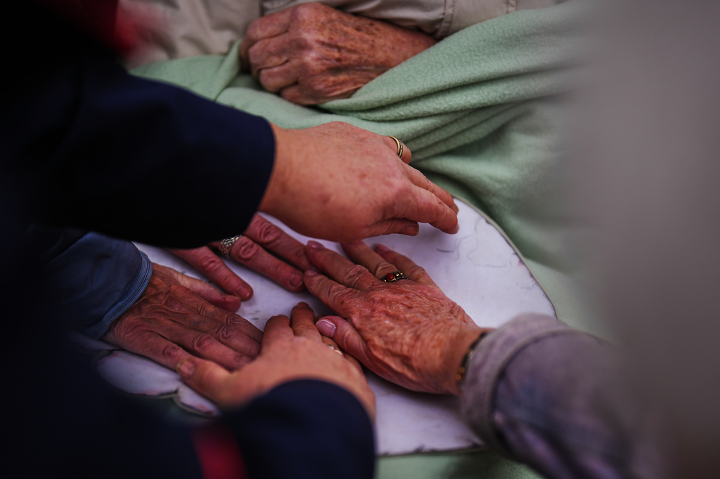 Participants and advisors put their hands on a cardboard box in the size of an elephant's foot during a guided tour for people with dementia organized by Malteser Deutschland, part of the international Catholic aid organization Malteser Order of Malta, at the Zoo in Berlin, Germany, Thursday, March 26, 2026. (AP Photo/Markus Schreiber)
