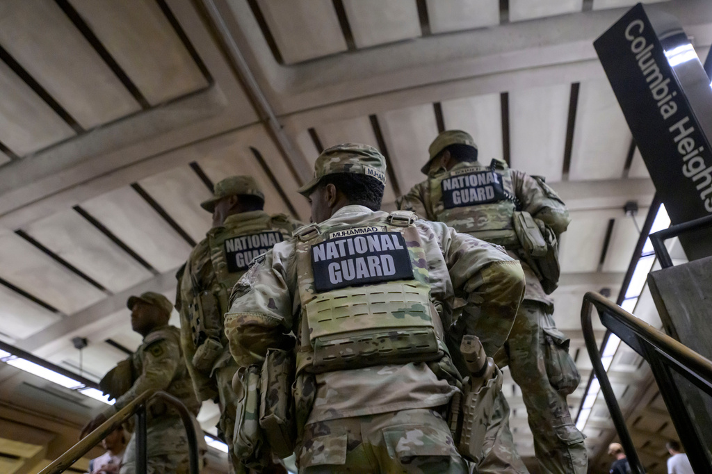 Members of the Arkansas National Guard continue their patrol after carrying an elderly woman in her wheelchair down the steps to the train platform due to an out-of-service elevator at the Columbia Heights metro station, Monday, Aug. 10, 2026, in Washington. (AP Photo/Rod Lamkey, Jr.)