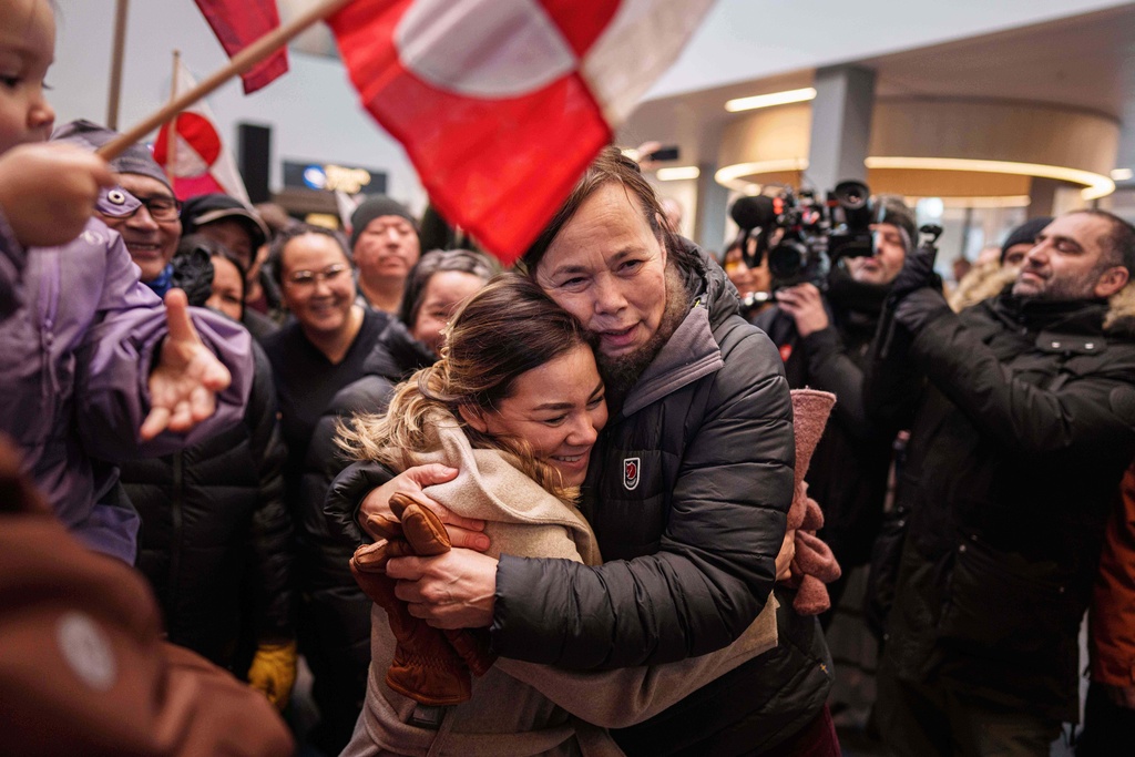 Greenland Minister for Foreign Affairs and Research Vivian Motzfeldt, center right, hugs a woman after arriving at the airport in Nuuk, Greenland, Tuesday, Jan. 20, 2026. (AP Photo/Evgeniy Maloletka)