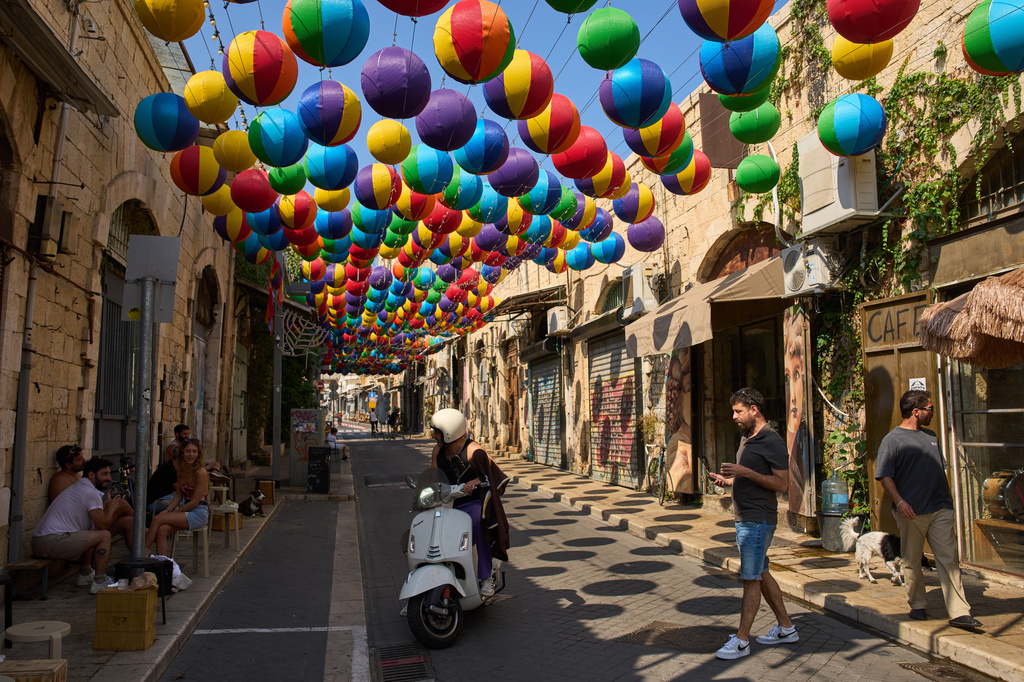 People walk beneath an art installation of colorful spheres along a pedestrian street in Jaffa, a mixed Jewish-Arab neighborhood of Tel Aviv, Israel, Sunday, Aug. 16, 2026. (AP Photo/Oded Balilty)