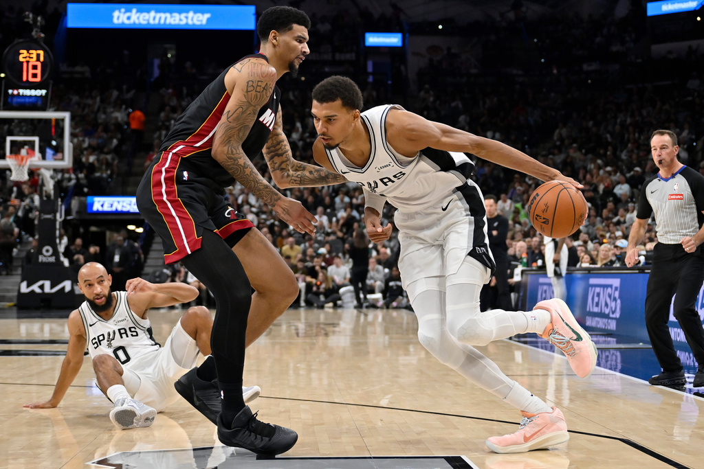San Antonio Spurs center Victor Wembanyama, right, drives against Miami Heat center Kel'el Ware, front left, during the second half of an NBA basketball game, Thursday, Oct. 30, 2025, in San Antonio. (AP Photo/Darren Abate)