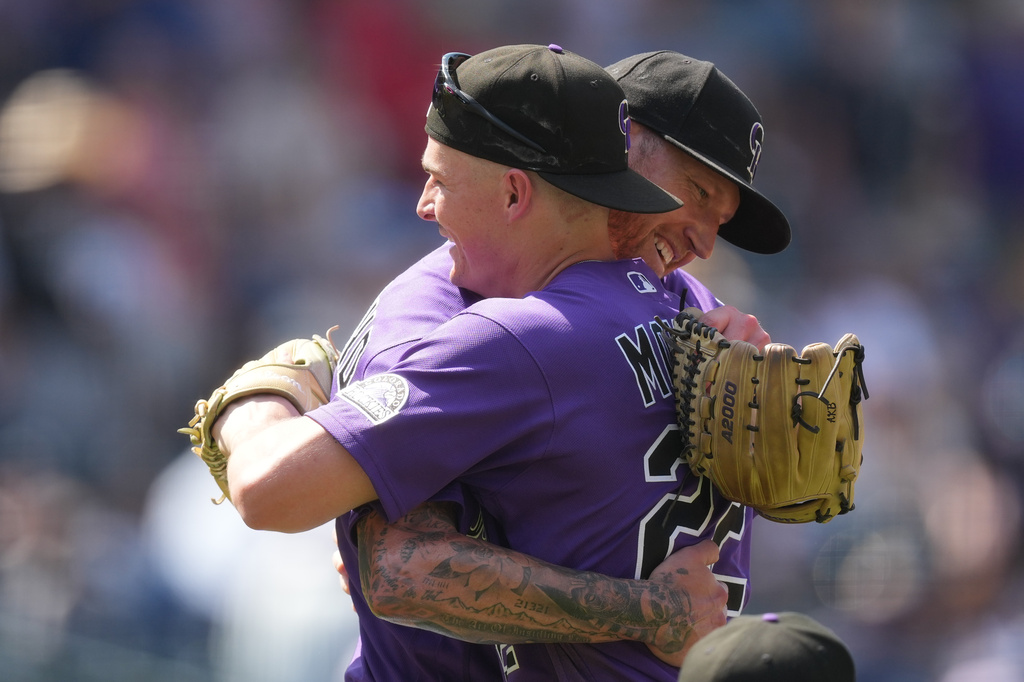 Colorado Rockies left fielder Mickey Moniak, front, hugs starting pitcher Kyle Freeland, back, after his complete baseball game victory over the Kansas City Royals, Sunday, Aug. 2, 2026, in Denver. (AP Photo/David Zalubowski)