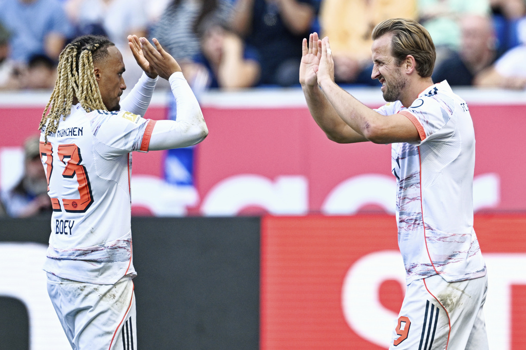 Bayern's Harry Kane, right, celebrates with Sacha Boey scoring their side's second goal of the game from a penalty during the German Bundesliga soccer match between Hoffenheim and Bayern Munich at the PreZero Arena in Sinsheim, Germany, Saturday Sept. 20, 2025. (Uwe Anspach/dpa via AP)