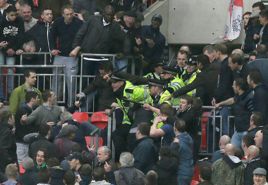 FILE - Police officers raise their battens as they control the crowd as Millwall play Wigan Athletic during their English FA Cup semifinal soccer match at Wembley stadium in London, Saturday, April 13, 2013. (AP Photo/Alastair Grant, file)