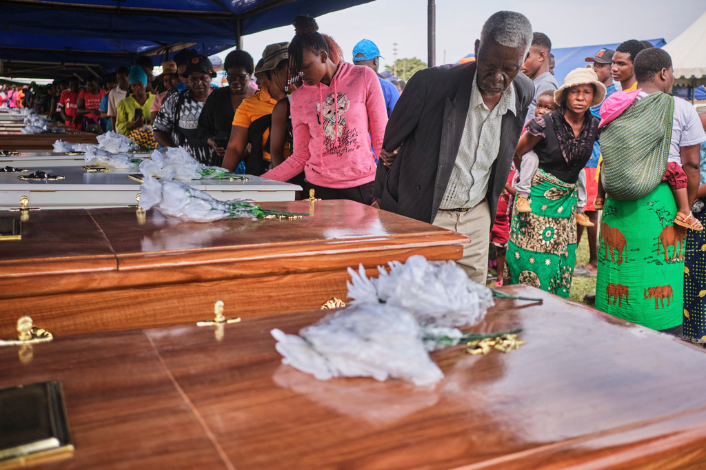 Family members walk past caskets carrying their loved ones during a memorial service for the victims of a ferry that capsized on Lake Kariba in Kariba, Zimbabwe, Thursday, Aug. 13, 2026. (AP Photo/Mkhululi Thobela)