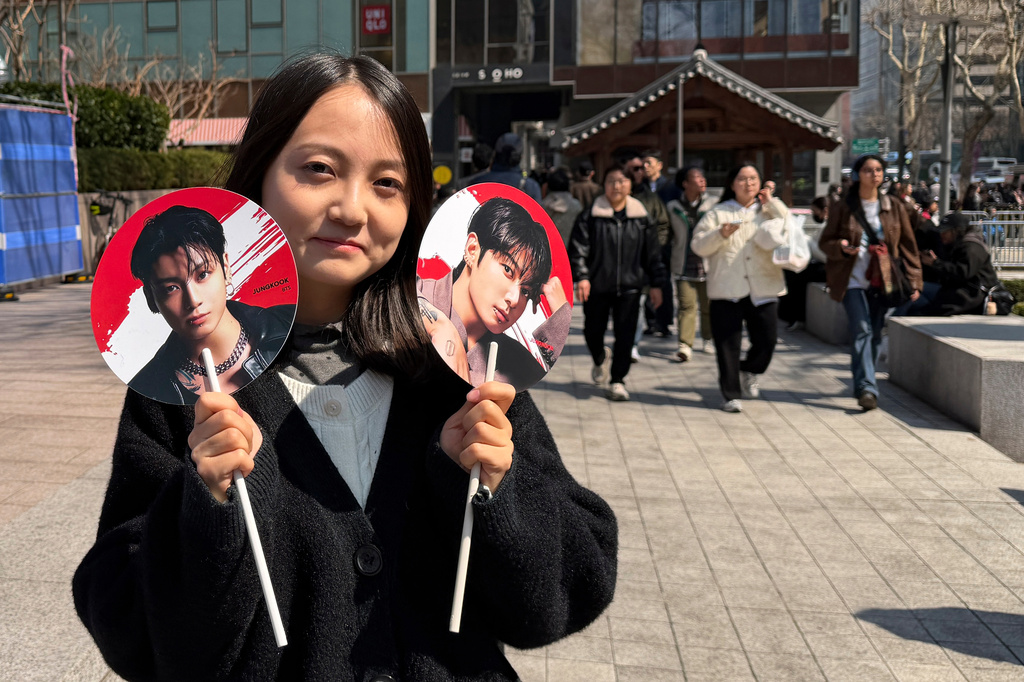 Tian Xin, a BTS fan from Gansu province, China, poses for a photo with handheld fans featuring BTS member Jung Kook, ahead of BTS's comeback concert near Gwanghwamun Square in Seoul, South Korea, Saturday, March 21, 2026. (AP Photo/ Juwon Park)