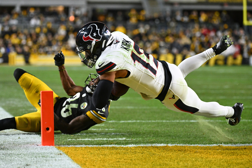Houston Texans wide receiver Christian Kirk (13) dives in to the end zone for a touchdown while defended by Pittsburgh Steelers cornerback Brandin Echols (26) during the first half of an NFL wild-card playoff football game, Monday, Jan. 12, 2026, in Pittsburgh. (AP Photo/Justin Berl)
