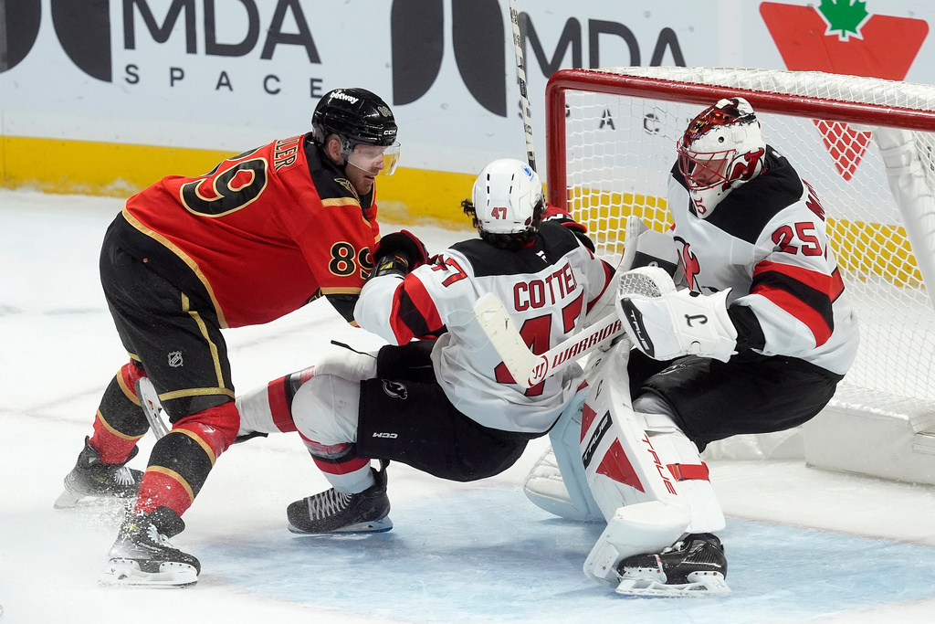New Jersey Devils left wing Paul Cotter (47) crashes into his own goaltender Jacob Markstrom (25) as he battles with Ottawa Senators centre Lars Eller (89) during second period NHL game, in Ottawa, Tuesday, Dec. 9, 2025. (Adrian Wyld/The Canadian Press via AP)