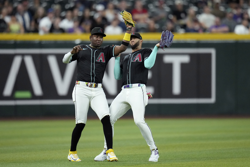 Arizona Diamondbacks shortstop Geraldo Perdomo, left, makes a catch on a pop fly hit by Cleveland Guardians' Daniel Schneemann as Perdomo avoids colliding with Diamondbacks left fielder Lourdes Gurriel Jr., right, during the first inning of a baseball game Monday, Aug. 18, 2025, in Phoenix. (AP Photo/Ross D. Franklin)
