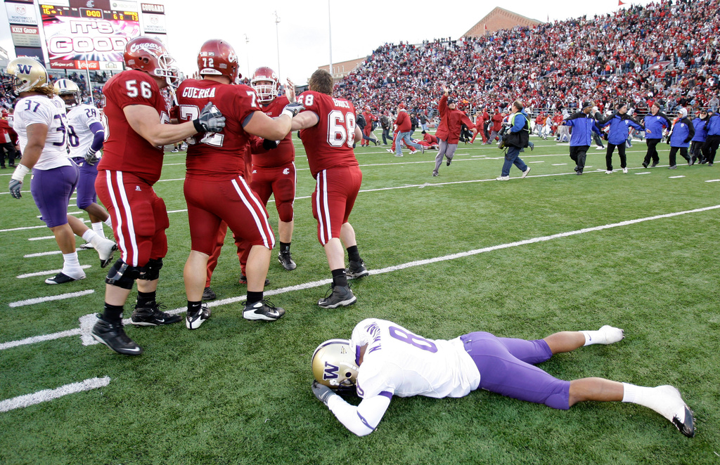 FILE - Washington free safety Nate Williams lies on the ground as Washington State players celebrate their win over Washington in double overtime, in the NCAA college football Apple Cup, Nov. 22, 2008, at Martin Stadium in Pullman, Wash. (AP Photo/Ted S. Warren, File)