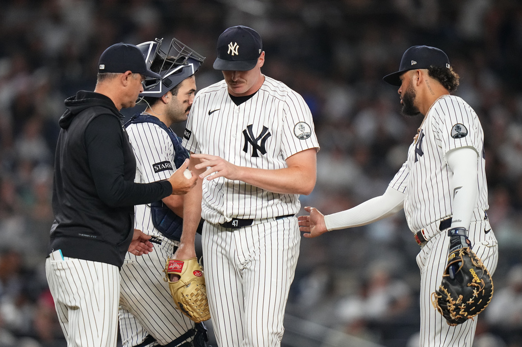 New York Yankees pitcher Brent Headrick, center, hands the ball to manager Aaron Boone, left, as he leaves during the eighth inning of a baseball game against the Houston Astros Tuesday, Aug. 25, 2026, in New York. (AP Photo/Frank Franklin II)