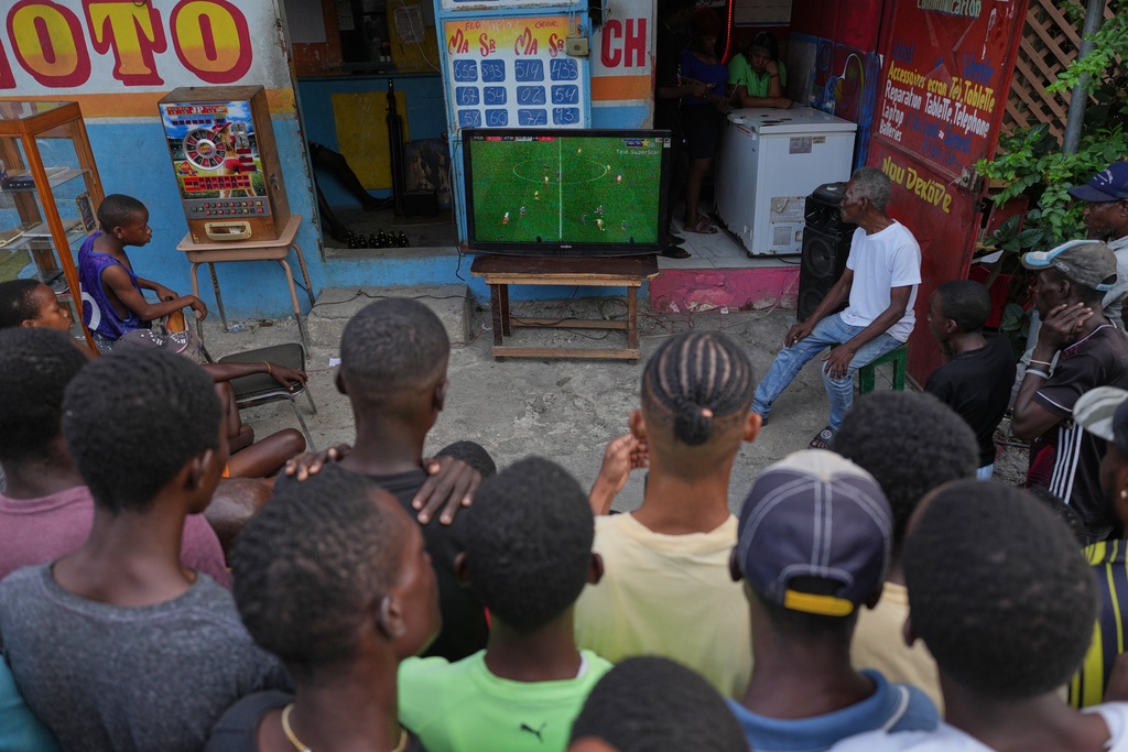 FILE - People watch a soccer match between FC Barcelona and Atlético Madrid on a sidewalk in downtown Port-au-Prince, Haiti, March 3, 2026. (AP Photo/Odelyn Joseph, File)