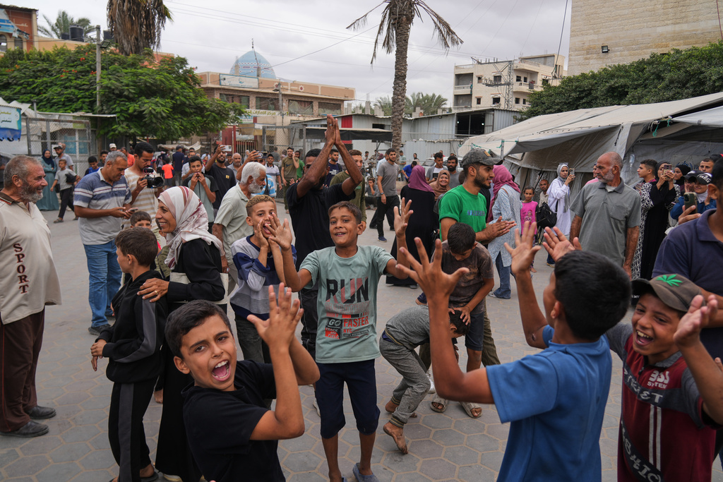 Palestinians celebrate following the announcement that Israel and Hamas have agreed to the first phase of a peace plan to pause the fighting, outside Al-Aqsa Hospital in Deir al-Balah, central Gaza Strip, Thursday, Oct. 9, 2025. (AP Photo/Abdel Kareem Hana)