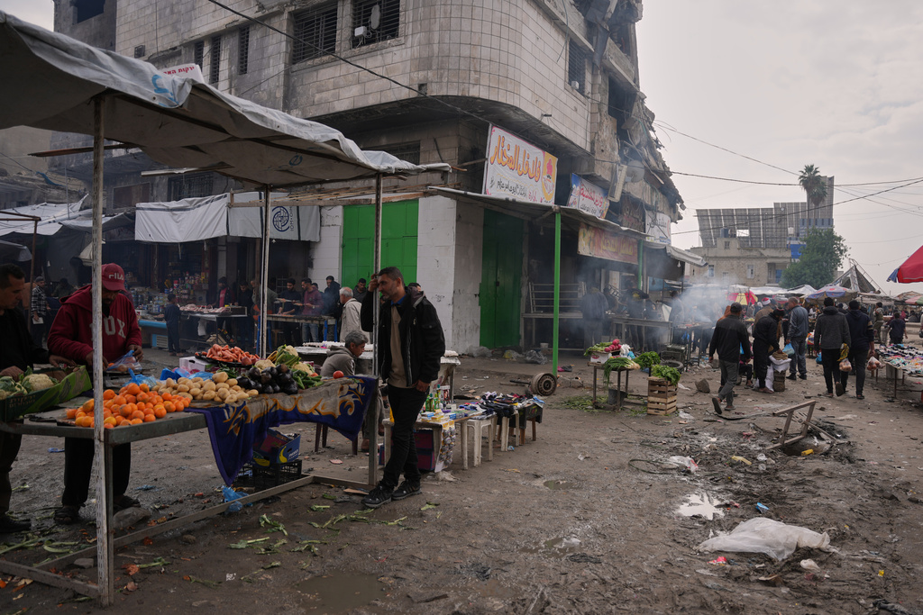Palestinians walk along street market where fruits and vegetables are displayed for sale in Gaza City, Friday, Dec. 19, 2025. (AP Photo/Abdel Kareem Hana)