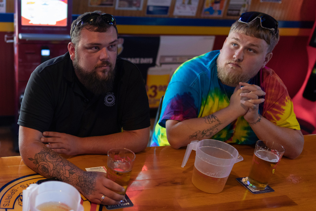 UAW Local 402 members Chaz Graham, left, and Kyle Bos, right, share a beer at Fricker's restaurant and bar in Springfield, Ohio, on Wednesday, Sept. 30, 2026, on old Navistar's last day at its Springfield plant. (AP Photo/Carolyn Kaster)