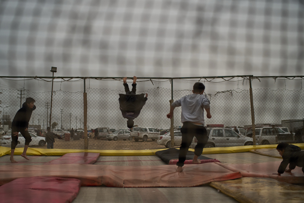 Kids play on a trampoline at Kawa Camp, which houses Iranian Kurdish refugees who fled Iran following the 1979 Islamic Revolution, in the outskirts of Irbil, Iraq, Saturday, March 14, 2026. (AP Photo/Leo Correa)