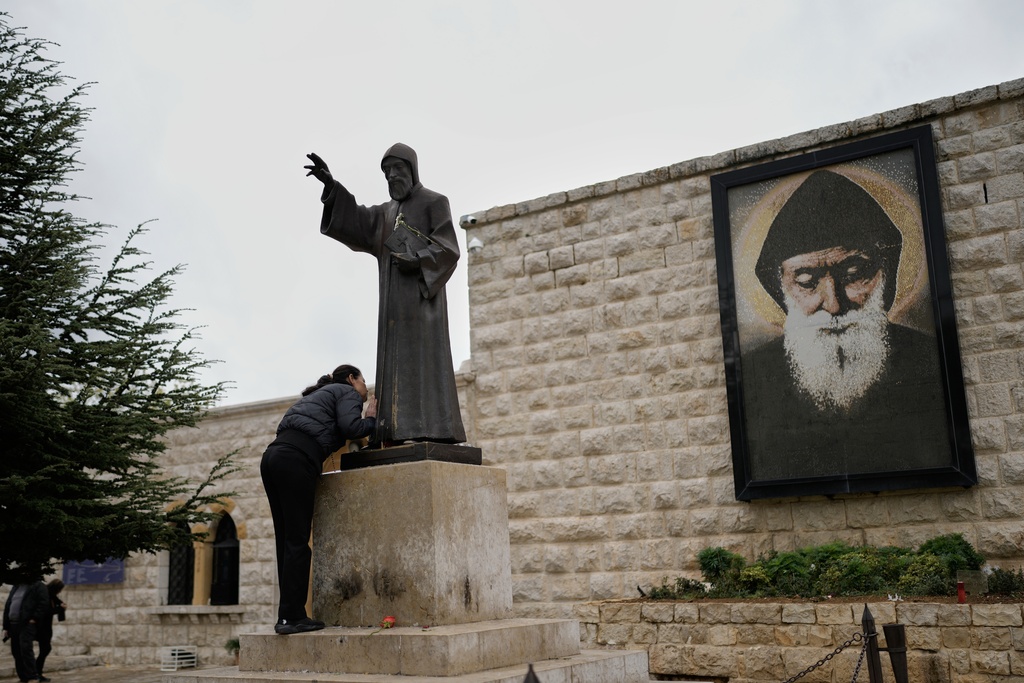 A worshipper kisses the statue of St. Charbel, a 19th-century Maronite monk, at his shrine in the northern village of Annaya, Lebanon, Saturday, Nov. 15, 2025. (AP Photo/Hassan Ammar)