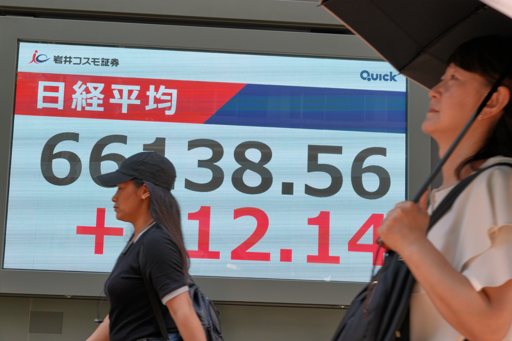 People walk in front of an electronic stock board showing Japan's Nikkei index at a securities firm Thursday, Aug. 20, 2026, in Tokyo. (AP Photo/Eugene Hoshiko)
