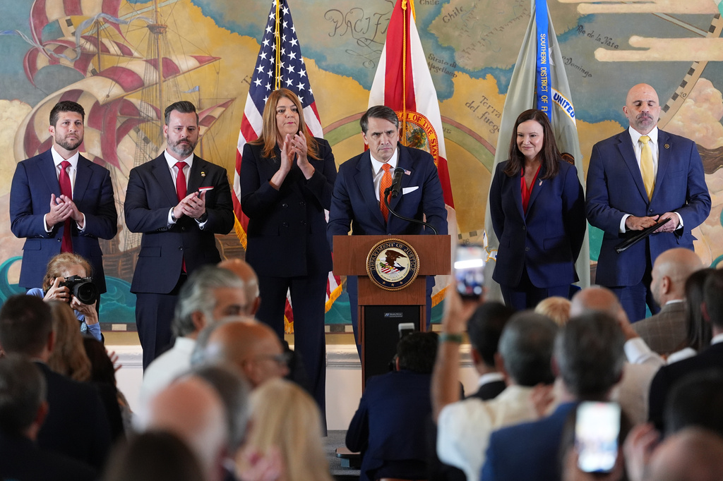 Audience members give a standing ovation as Acting Attorney General Todd Blanche, center, speaks at an event where federal prosecutors announced charges against former Cuban President Raul Castro in the 1996 downing of civilian planes operated by Miami-based exiles, Wednesday, May 20, 2026, in Miami. Also shown, from left, are, Florida Attorney General James Uthmeier; Jason A. Reding Quiñones, U.S. attorney for the southern district of Florida; Miami Dade College President Madeline Pumariega; Sen. Ashley Moody, R-Fla.; and FBI Deputy Director Christopher Raia. (AP Photo/Rebecca Blackwell)