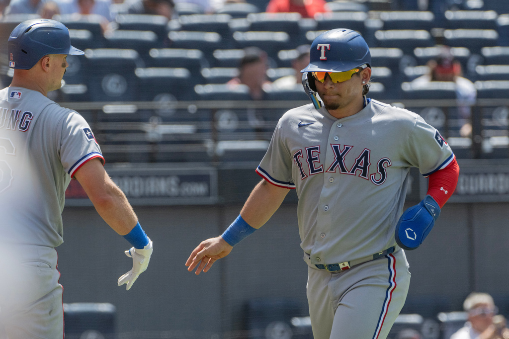 Texas Rangers' Alejandro Osuna, right, is greeted by Josh Jung, left, after scoring on a double by Nicky Lopez during the sixth inning of a baseball game against the Cleveland Guardians, Wednesday, July 1, 2026, in Cleveland. (AP Photo/Phil Long)