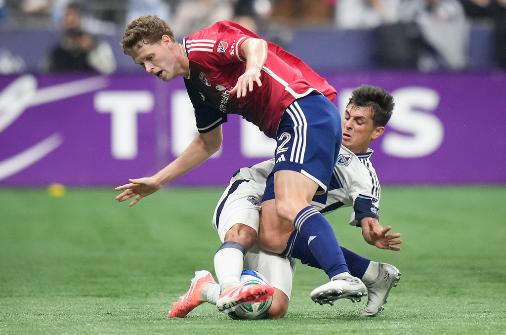 FC Dallas' Christian Cappis, top, and Vancouver Whitecaps' Andres Cubas, bottom, vie for the ball during the first half in Game 1 in the first round of MLS soccer's Western Conference playoffs in Vancouver, British Columbia, Sunday, Oct. 26, 2025. (Darryl Dyck/The Canadian Press via AP)