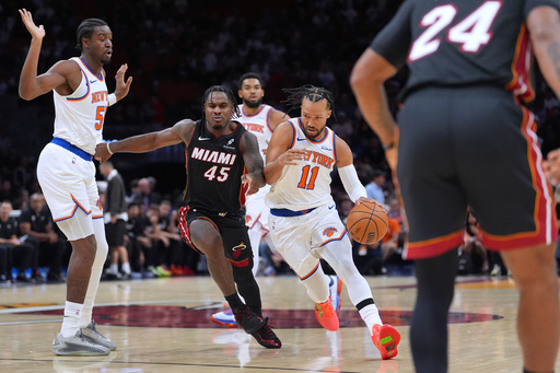 New York Knicks guard Jalen Brunson (11) drives forward defended by Miami Heat guard Davion Mitchell (45) as New York Knicks center Ariel Hukporti, left, looks on during the first half of an NBA basketball game, Sunday, Oct. 26, 2025, in Miami. (AP Photo/Rebecca Blackwell) New York Knicks guard Jalen Brunson (11) drives forward defended by Miami Heat guard Davion Mitchell (45) as New York Knicks center Ariel Hukporti, left, looks on during the first half of an NBA basketball game, Sunday, Oct. 26, 2025, in Miami. (AP Photo/Rebecca Blackwell)