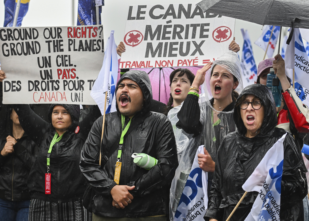 Air Canada employees and union members protest outside the Air Canada headquarters in Montreal, Sunday, Aug. 17, 2025, after the federal government intervened in the labour dispute between the airline and the union representing its flight attendants, ordering binding arbitration and operations to resume. (Graham Hughes/The Canadian Press via AP)