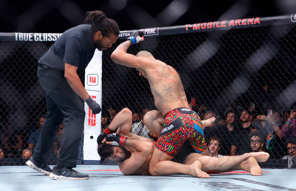 Alex Pereira, right, of Brazil, hits UFC light heavyweight champion Magomed Ankalaev, of Russia, as the referee looks on during the UFC 320 mixed martial arts bout Saturday, Oct. 4, 2025, in Las Vegas. (Steve Marcus/Las Vegas Sun via AP)
