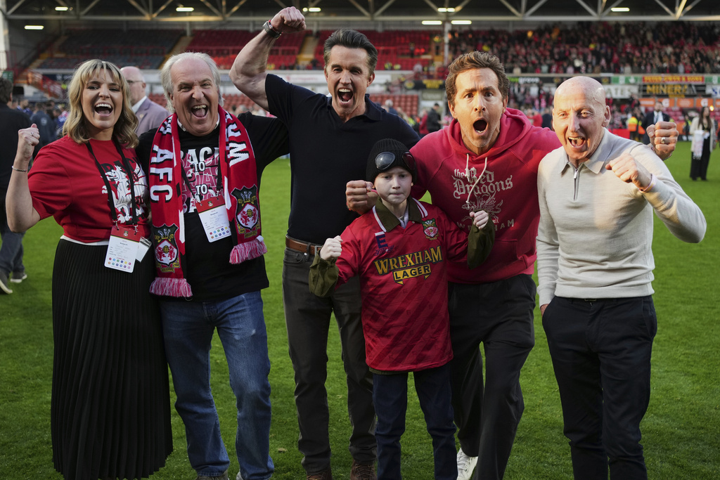 FILE - Wrexham co-owners Rob McElhenney, center, and Ryan Reynolds, second right, celebrate at the end of the English League One soccer match between Wrexham and Charlton Athletic at the Racecourse ground in Wrexham, Wales, April 26, 2025. (AP Photo/Jon Super, File)