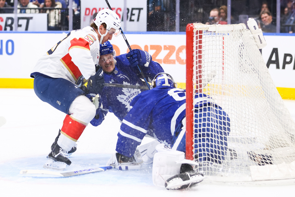Florida Panthers' Cole Reinhardt, left, collides with Toronto Maple Leafs' Jake McCabe (22) in front of Maple Leafs goaltender Joseph Woll, right, during first-period NHL hockey game action in Toronto, Saturday, April 11, 2026. (Cole Burston/The Canadian Press via AP)
