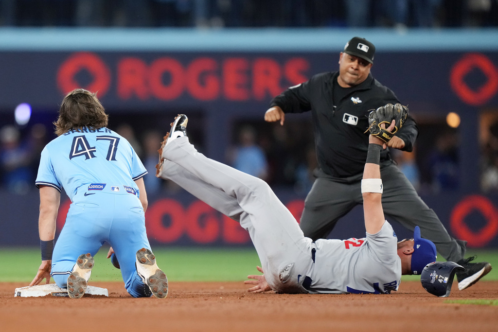 Los Angeles Dodgers second baseman Miguel Rojas (72) shows the ball to the umpire after forcing out Toronto Blue Jays' Addison Barger (47) at second to turn a double play to end the game during ninth inning Game 6 World Series playoff MLB baseball action in Toronto on Friday, Oct. 31, 2025. (Nathan Denette/The Canadian Press via AP)