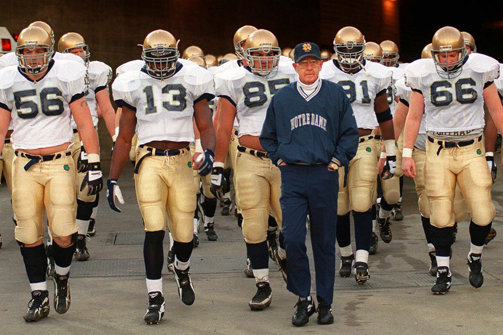 FILE - Notre Dame's head coach Lou Holtz and the Fighting Irish walk onto the field of the Los Angeles Coliseum to warm up for an NCAA college football game against Southern California Saturday, Nov. 30, 1996 in Los Angeles. (AP Photo/Kevork Djansezian, File)
