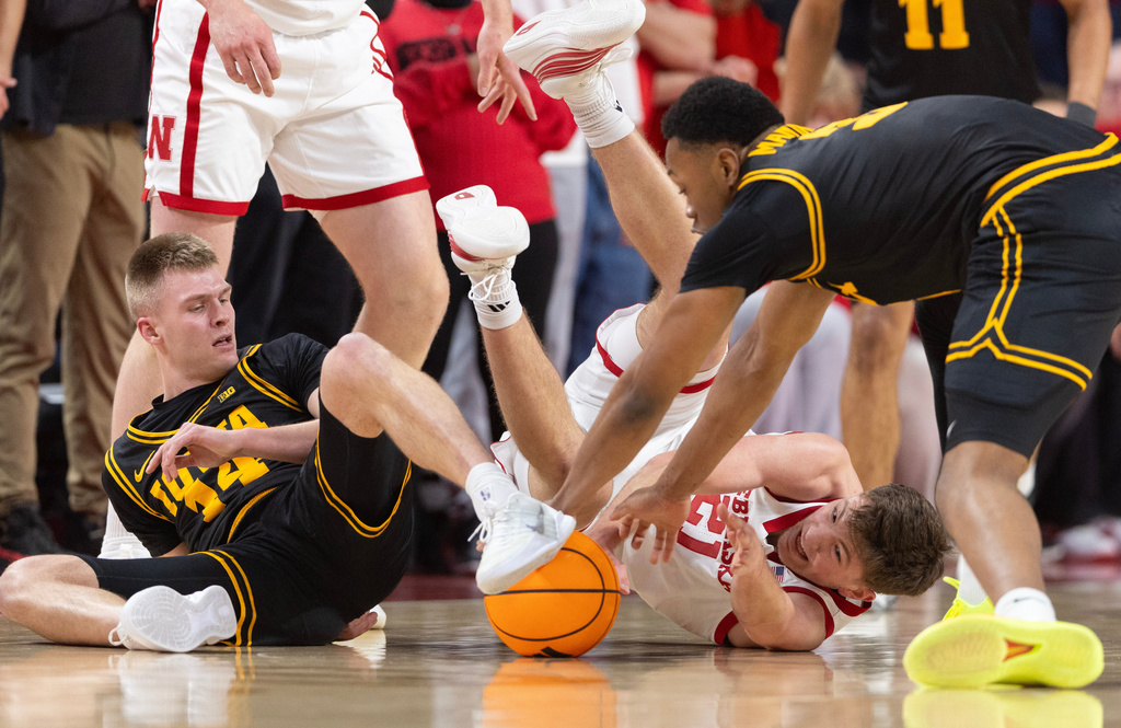 Iowa's Bennett Stirtz, left, and Cam Manyawu dive for a loose ball against Nebraska's Pryce Sandfort during the first half of an NCAA college basketball game, Sunday, March 8, 2026, in Lincoln, Neb. (AP Photo/Rebecca S. Gratz)