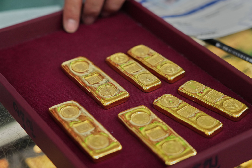 A customer puts gold bars on a basket at a gold shop in Bangkok, Thailand, Thursday, Jan. 29, 2026. (AP Photo/Sakchai Lalit)
