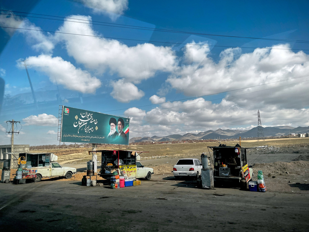 Vendors sell fruit, food and hot beverages along Road 2 next to a billboard depicting Iran's Supreme Leader Mojtaba Khamenei, right, and his father, slain Ayatollah Ali Khamenei, near Zanjan, Iran, Thursday, April 9, 2026. (AP Photo/Francisco Seco)