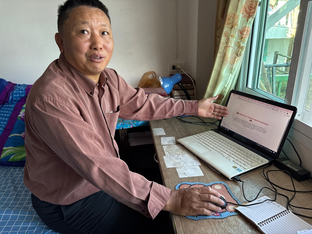 Lu Taizhi, a Chinese Christian who is waiting to be resettled in the United States, points to the webpage of the International Rescue Committee, which is under maintenance and not operational in Ban Wawee village, Chiang Rai Province, Thailand, Nov. 27, 2025. (AP Photo/ Tian Macleod Ji)