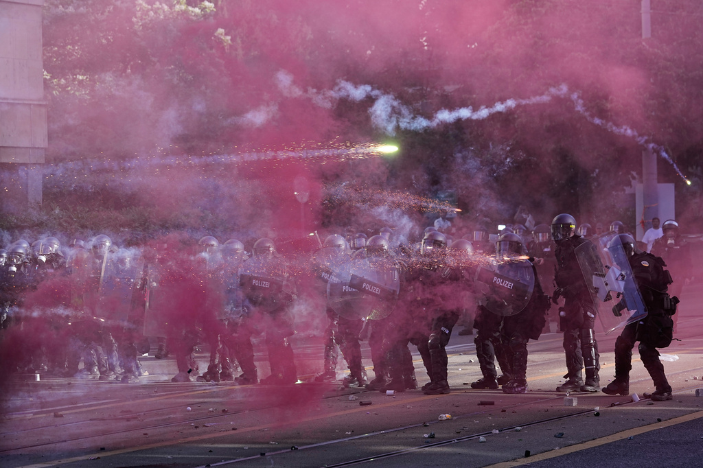 Flares are thrown at police during a "No G7" demonstration in Geneva, Switzerland, Sunday, June 14, 2026, ahead of the G7 summit scheduled to take place June 15-17. (AP Photo/Laurent Cipriani)
