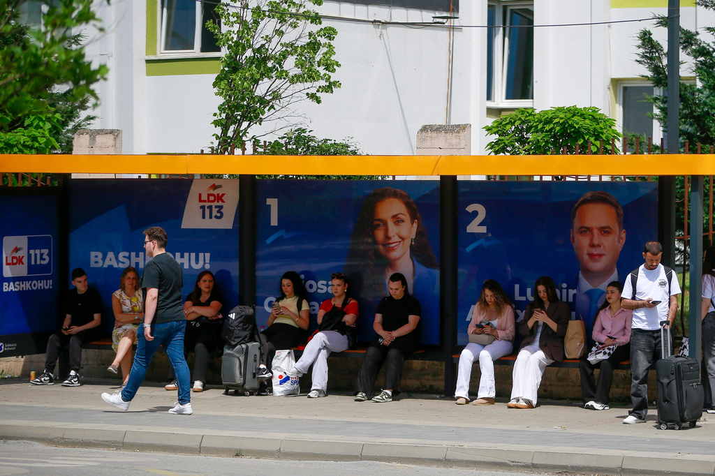 People wait at a bus station displaying election posters in capital Pristina, Kosovo, Friday, June 5, 2026, ahead of snap parliamentary elections on June 7. (AP Photo/Visar Kryeziu)