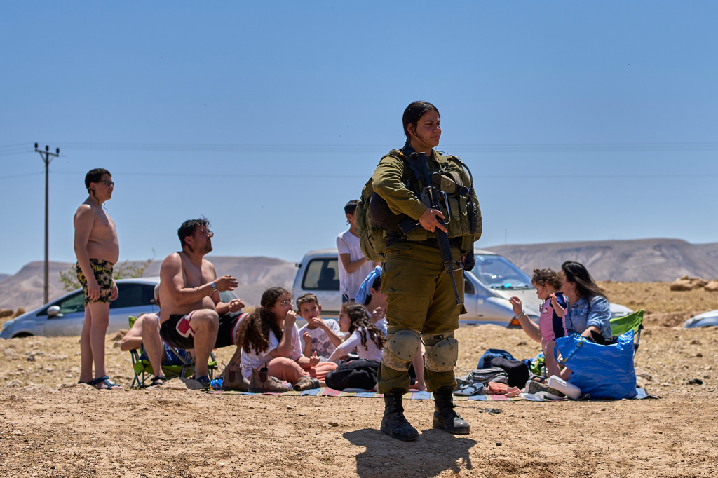 An Israeli soldier stands as Israeli settlers and others enjoy a day at a spring in the Jordan Valley during Israel's Independence Day, in Auja, in the occupied West Bank, Wednesday, April 22, 2026.(AP Photo/Ohad Zwigenberg)
