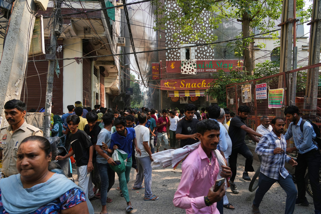 Locals and bystanders run for cover as a hotel fire spreads following electrical sparks in New Delhi, India, Wednesday, June 3, 2026. (AP Photo/Manish Swarup)