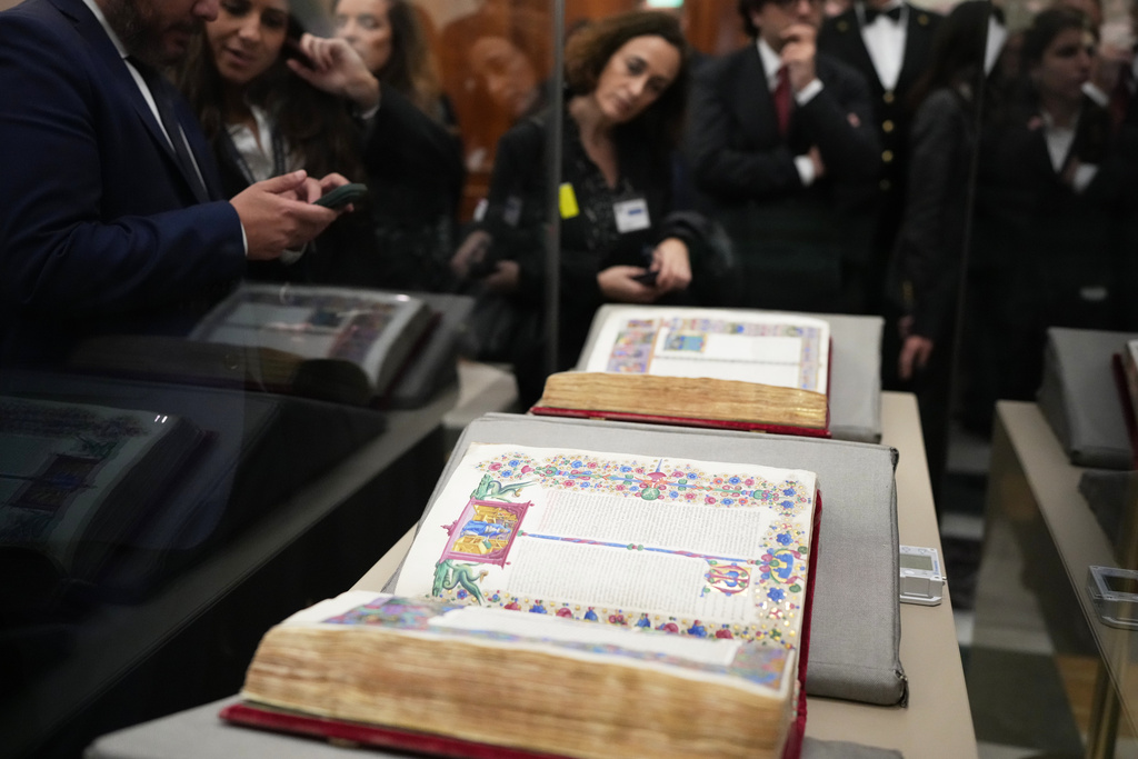 Reporters look at the 15th century Borso D'Este Bible, comprising two illuminated manuscripts, after its unveiling at the Italian Senate as part of the Vatican's Holy Year celebrations in Rome, Thursday, Nov. 13, 2025. (AP Photo/Alessandra Tarantino)