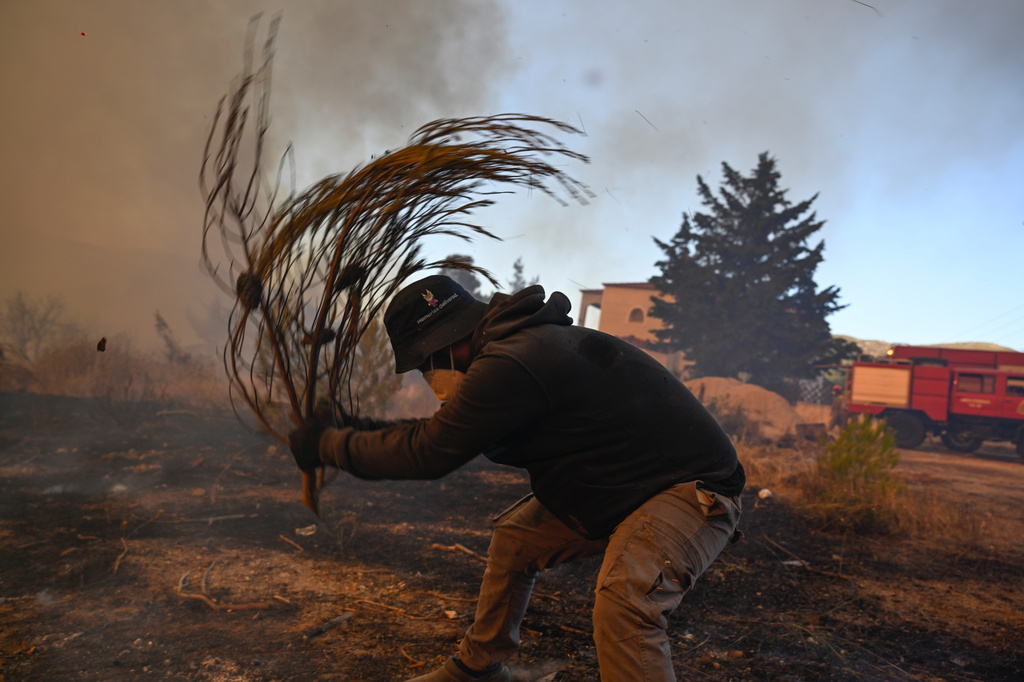 A volunteer tries to extinguish small flames during a wildfire near Porto Germeno, northwest of Athens, Greece, Sunday, Aug. 2, 2026. (AP Photo/Michael Varaklas)