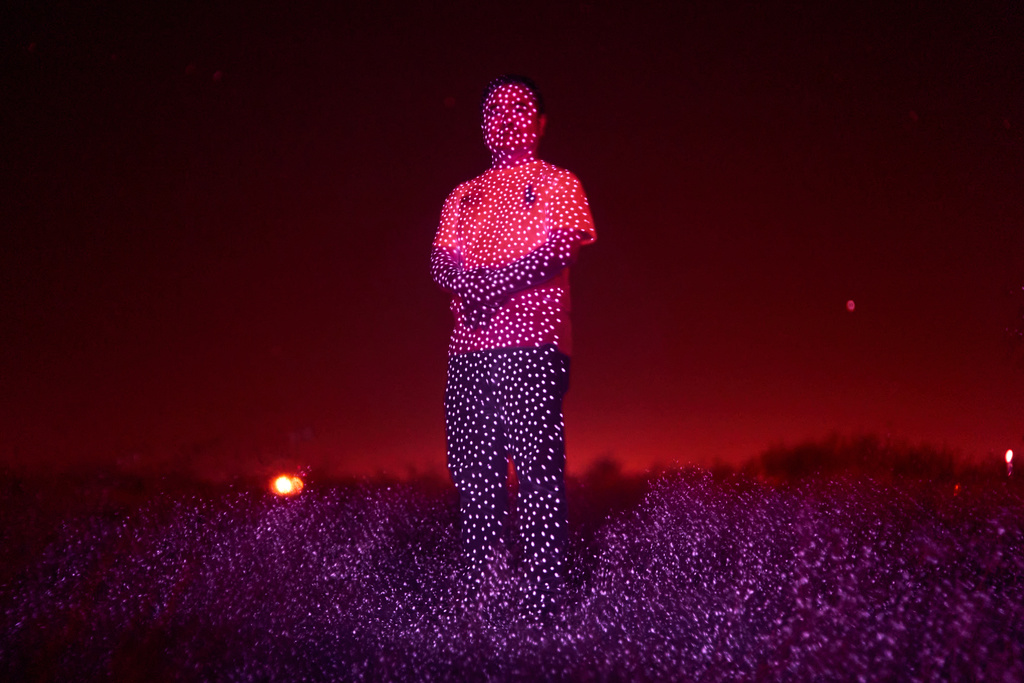Retired Chinese official Li Chuanliang, who openly criticized the Chinese government after seeing first-hand how surveillance technology built up the government's power and is now being accused of corruption by Beijing, is illuminated by cellphone infrared facial recognition beams as he stands for a photo in the oil fields of Midland, Texas, where he's currently living in exile, Oct. 11, 2025. (AP Photo/David Goldman)