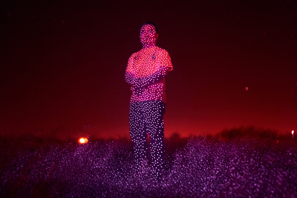 Retired Chinese official Li Chuanliang, who openly criticized the Chinese government after seeing first-hand how surveillance technology built up the government's power and is now being accused of corruption by Beijing, is illuminated by cellphone infrared facial recognition beams as he stands for a photo in the oil fields of Midland, Texas, where he's currently living in exile, Oct. 11, 2025. (AP Photo/David Goldman)