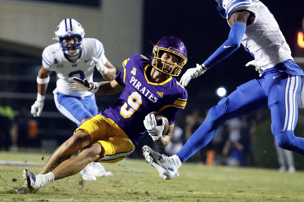 East Carolina wide receiver Anthony Smith (9) loses his footing between two BYU defenders during the first half of an NCAA college football game in Greenville, N.C., Saturday, Sept. 20, 2025. (AP Photo/Karl DeBlaker)
