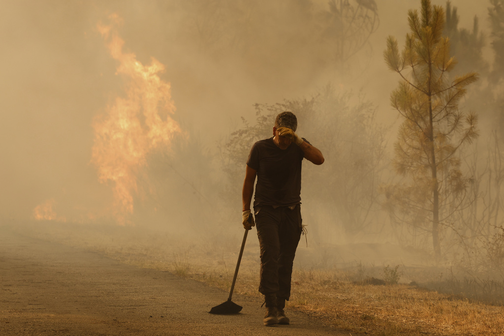 A volunteer reacts in front of a wildfire in Larouco, northwestern Spain, Wednesday, Aug. 13, 2025. (AP Photo/Lalo R. Villar)