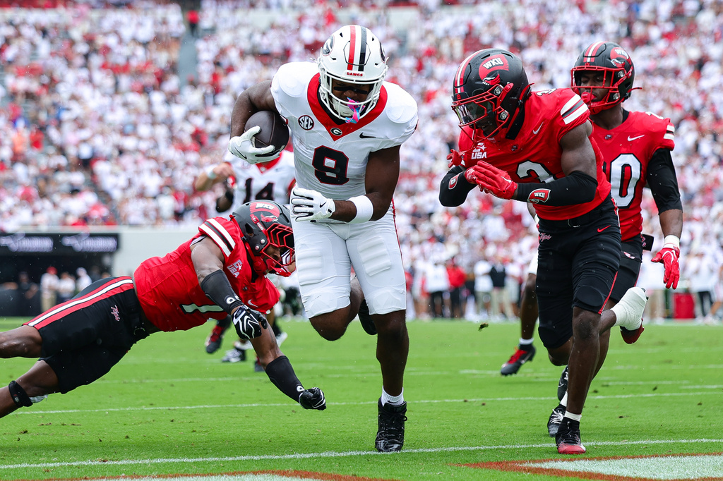 Georgia tight end Ethan Barbour (9) scores a touchdown against Western Kentucky defensive backs Jaylen Lewis, left, and Christian White, right, during the first half of an NCAA college football game, Saturday, Sept. 12, 2026, in Athens, Ga. (AP Photo/Colin Hubbard)