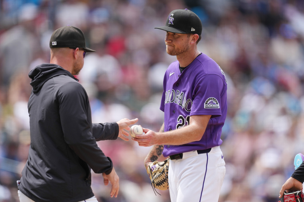 Colorado Rockies manager Warren Schaeffer, left, takes the ball from starting pitcher Kyle Freeland as he is pulled from the mound after issuing a bases-loaded walk to Atlanta Braves' Eli White in the fifth inning of a baseball game, Sunday, May 3, 2026, in Denver. (AP Photo/David Zalubowski)